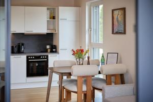 a kitchen with a table and chairs and a kitchen with white cabinets at VORALIVING - Modernes Neubau Apartment Toplage - Business & Urlaub - WLAN, 24 7 Check-in in Dornbirn