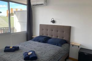a bedroom with a bed with blue pillows and a window at TIPANIER - City center room Papeete in Papeete