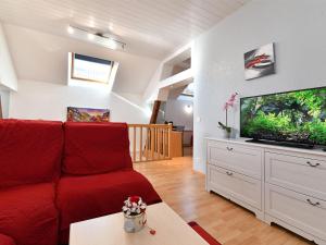 a living room with a red couch and a fish tank at Gîte convivial avec terrasse abritée, 3 chambres, cuisine équipée, espace détente, proche autoroutes et pistes cyclables. - FR-1-744-6 in Baldersheim