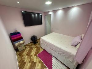 a bedroom with a bed and a flat screen tv at Casa rosa in Sao Paulo