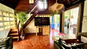 ein Wohnzimmer mit Fernseher und Treppe in der Unterkunft Linareva Moorea Beach Resort in Haapiti