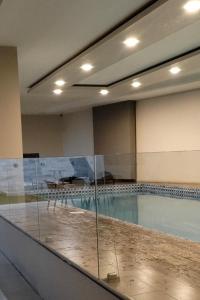コチャバンバにある3c Departamento en Torres Venturaのガラスの壁のスイミングプール付きの客室です。