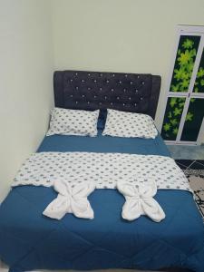 a bed with two white bows on top of it at Ameera family homestay in Bachok