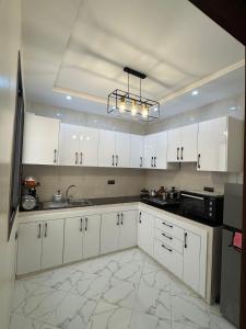 a kitchen with white cabinets and a sink at Cozy Bright Family Apartment Near City Center in Tagadirt