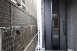 a metal fence next to a building with a door at Tabi in Tokyo in Tokyo