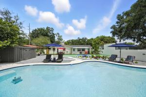 タンパにあるLuxury Oasis Retreat Pickleball Pool Spa Billiard Gamingのスイミングプール(椅子2脚、パラソル付)