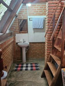 a bathroom with a sink in a brick wall at Chalé Aconchegante, Tapiraí-SP in Tapiraí