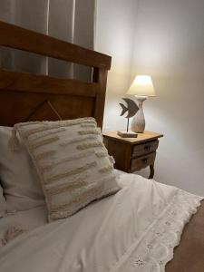 a bed with a white pillow and a table with a lamp at Apartamento Paraiso Búzios l in Rio de Janeiro