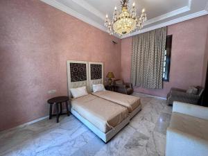 マラケシュにあるVilla de Charme avec Piscine, Hammam & Jardin Enchantéの大きなベッドとシャンデリアのある寝室