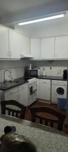 a kitchen with white cabinets and a table with chairs at Coração das Furnas in Furnas