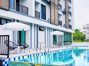 a swimming pool with chairs and umbrellas next to a building at Family room in Baan Pakdi Pattaya in Pattaya Central