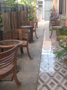 a row of wooden chairs and tables on a patio at PENDIK Home Stay in Labuan Bajo