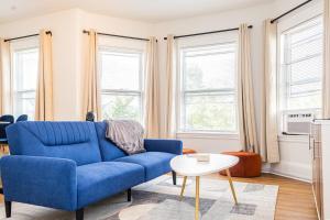 a blue couch in a living room with windows at Spacious 3BR Family Flat Near Encore Assembly Row in Somerville +23 photos