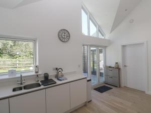 a kitchen with white cabinets and a clock on the wall at Kerrek Lodge in Falmouth