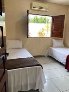 two beds in a room with a window at Casa Porto in Porto De Galinhas +18 photos
