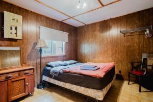 - une chambre avec des murs en bois, un lit et une lampe dans l'établissement 2-Bedroom Cottage #2 - Sand Bay, à Dillon 4 autres photos
