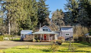 a house with a red door in a yard at Cozy vibes, hot tub, EV charger, 1mi to beach in Westport