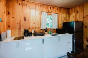 une cuisine avec des murs en bois et un réfrigérateur noir dans l'établissement 2-Bedroom Cottage #6 - Sand Bay, à Dillon