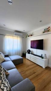 Una sala de estar con un sofá y un televisor de pantalla plana. en Charming Cottage Retreat Penrith, en Penrith