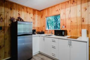 une cuisine avec des armoires blanches et un réfrigérateur en acier inoxydable dans l'établissement 2-Bedroom Cottage #11 - Sand Bay, à Dillon