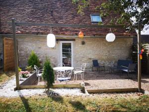 un patio avec une table et des chaises devant une maison dans l'établissement Evasion et nature près de Châteauroux, logez au cœur du Berry - FR-1-591-763, à Meunet-Planches