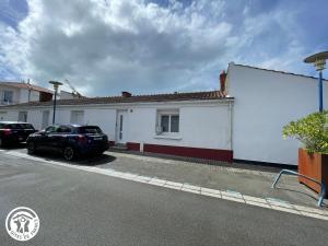 ein weißes Gebäude mit einem auf einem Parkplatz geparkten Auto in der Unterkunft Maison climatisée proche plage à Saint-Hilaire-de-Riez - FR-1-426-591 in Saint-Hilaire-de-Riez + 8 Fotos