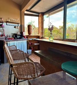 Una cocina con sillas de mimbre y un mostrador con encimera. en Vila Kuir Hospedagens, en Alto Paraíso de Goiás