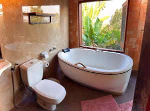 Un baño con bañera, inodoro y ventana. en Vila Kuir Hospedagens, en Alto Paraíso de Goiás 47 fotos más