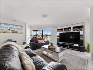 un salon avec un canapé et une télévision à écran plat dans l'établissement Private Jetty -family & Pet Friendly, à Mandurah