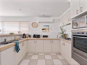 a white kitchen with white cabinets and a sink at Private Jetty -family & Pet Friendly in Mandurah
