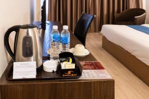 Una habitación de hotel con cafetera y botellas de agua. en Somerset Hotel, en Miri