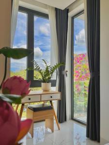 Cette chambre dispose d'un bureau et d'une fenêtre ornée de fleurs roses. dans l'établissement D & A Homestay Hue, à Hue