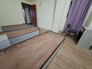 Una habitación con tres camas y una silla dentro. en KTM Homestay, en Katmandú
