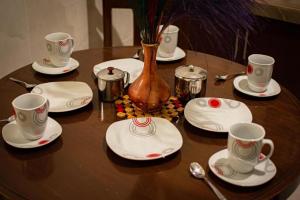 a wooden table with plates and cups and a vase at Departamento comodo y centrico en la llajta in Cochabamba +11 photos