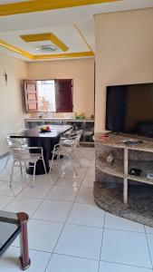 a living room with a table and a large screen tv at Casa Porto in Porto De Galinhas