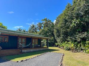 a blue house with a porch and trees at Amori Cabin in Arorangi
