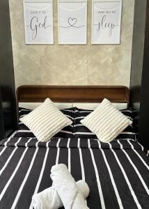 a bed with two stuffed animals on it with three pictures on the wall at Ellie's Tiny House - Cozy Getaway with Kitchen & Pool Access near SM Dasmariñas in Dasmariñas