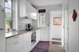 a white kitchen with white cabinets and a rug at 5644-Gudhjem-Holkavej-13-B in Gudhjem