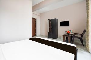 a bedroom with a bed and a chair and a television at Hotel O Aasiyanaa Guest House in Bhubaneshwar