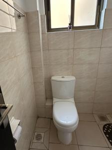 a white toilet in a bathroom with a window at The white cottage in Kitengela 