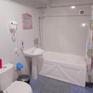 a bathroom with a white tub and a sink and a toilet at Mekhtarin in Bukhara