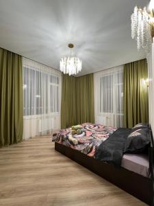 a bedroom with a bed with green curtains and a chandelier at Апартаменты в центре Астаны in Astana
