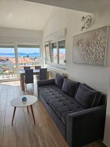 un salon avec un canapé noir et une table dans l'établissement Apartmani Lu, à Zadar