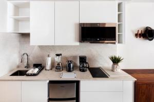 a kitchen with white cabinets and a sink and a microwave at Kadun Hotel Boutique in Cabo San Lucas