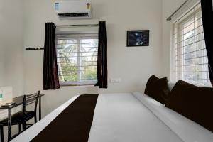 a bedroom with a bed and a table and window at Hotel O ELITE STAY in Navalur