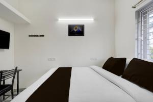 a bed in a white room with a picture on the wall at Hotel O ELITE STAY in Navalur +49 photos