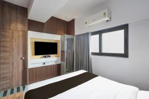 a bedroom with a bed and a tv on the wall at Hotel O The Faam in Rajkot