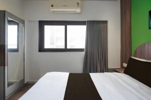 a bedroom with a large bed and a window at Hotel O The Faam in Rajkot