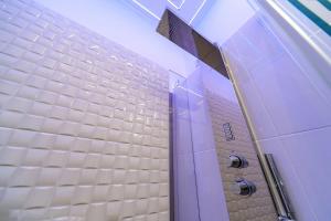 uma casa de banho com paredes em azulejos brancos e uma porta roxa em Guesthouse Pop em Roma mais 27 fotografias
