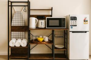 a kitchen shelf with a microwave and a refrigerator at Campbelltown Colonial Motor Inn in Campbelltown